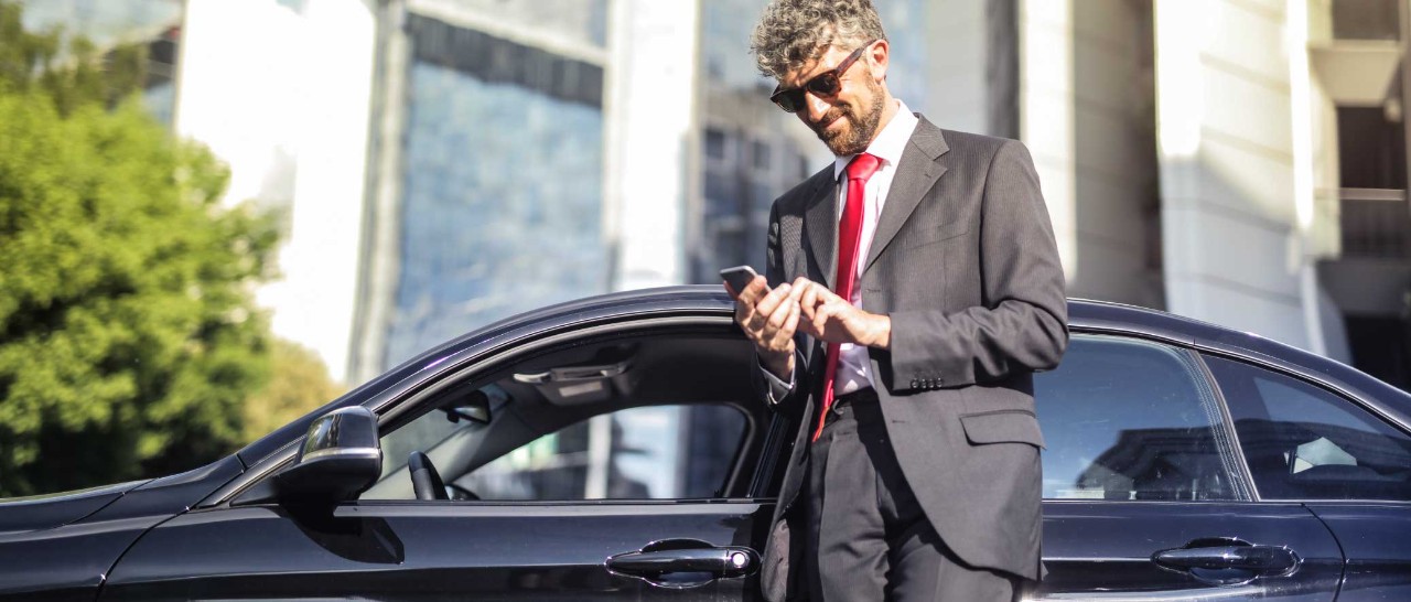 Man in suit on cellphone standing in front of car.