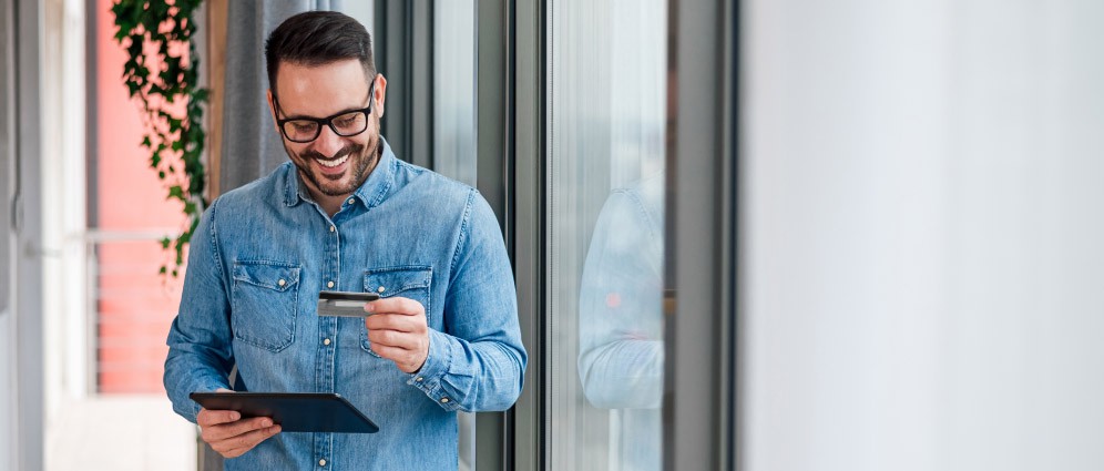 Man standing with credit card and tablet, applying for a credit line increase