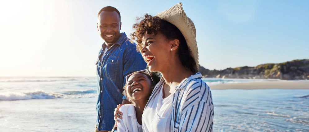 Family of three standing on beach, laughing together