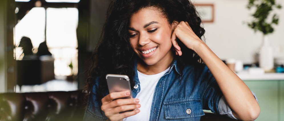 A woman smiling at her phone.