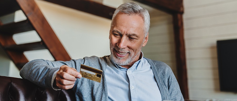 A man smiling at his credit card.