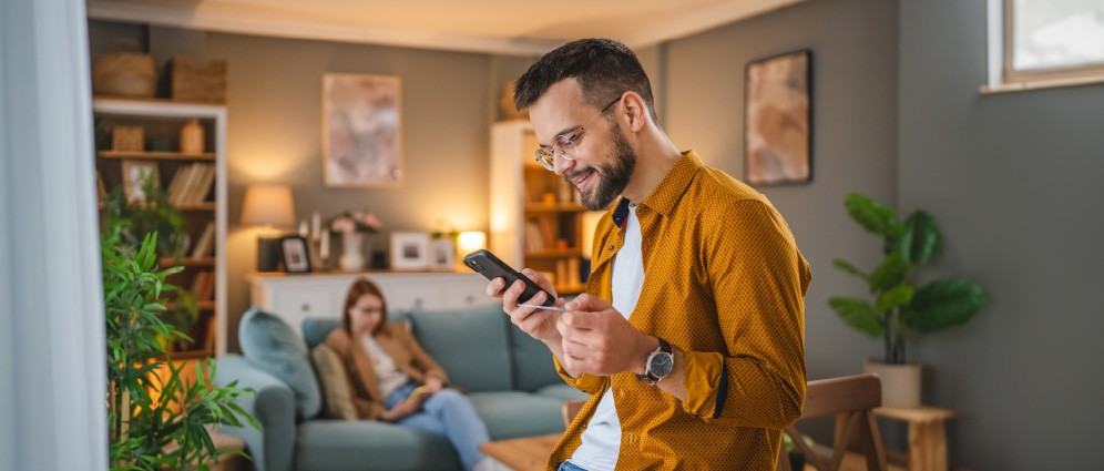 Man smiling holding a credit card and looking at his phone