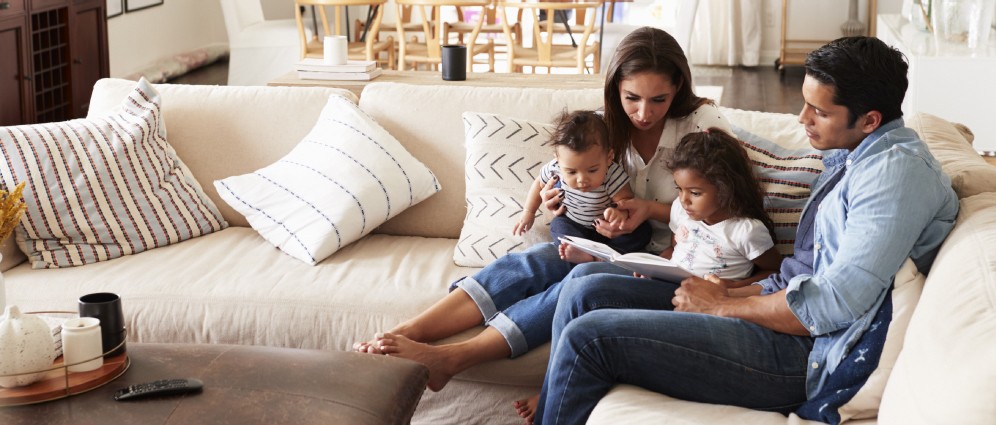 A family reading a book on the couch.