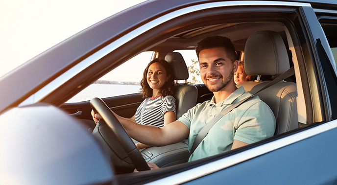 A family sitting in a car and smiling together