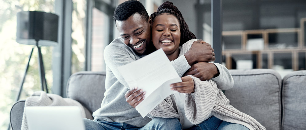 couple sitting down together excited while the woman holds a paper