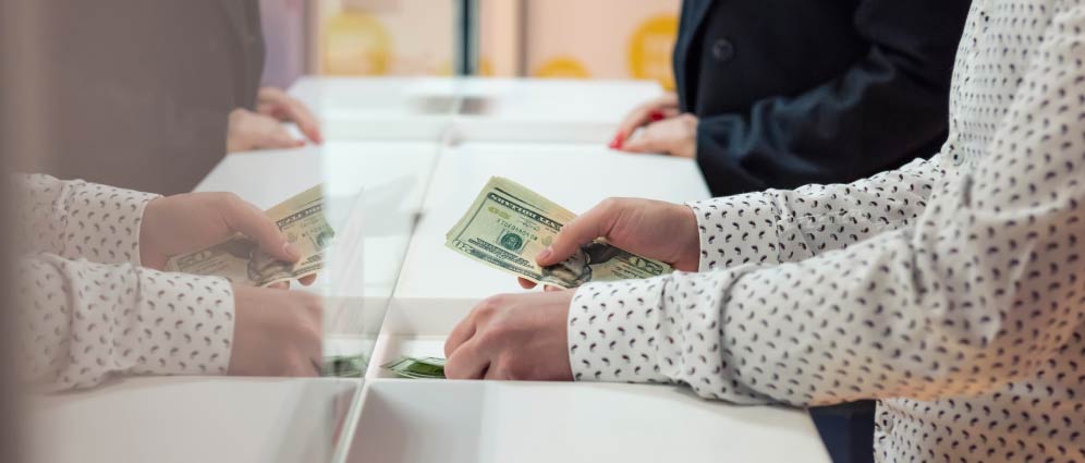 Person handing cash to teller at service counter