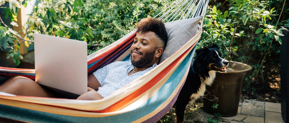 A man lying in a hammock with a laptop