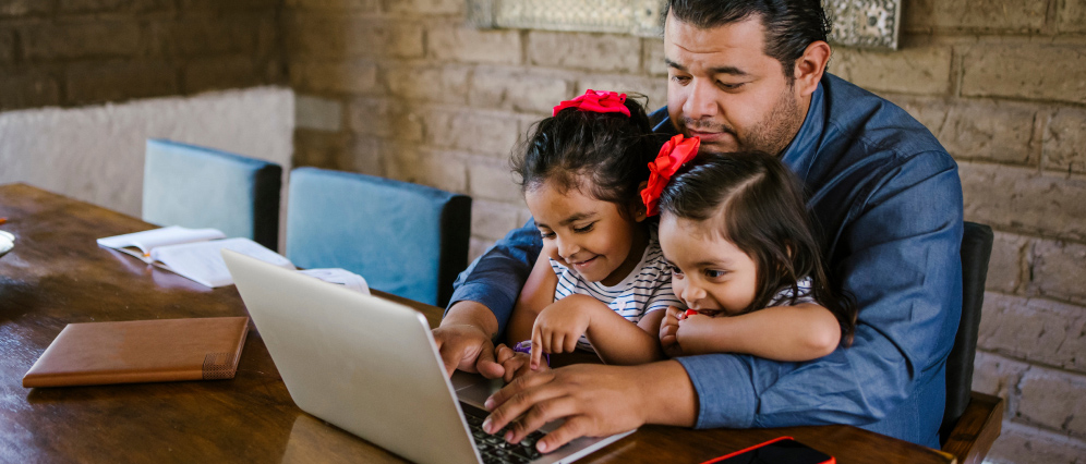 A father with his two daughters using a laptop.