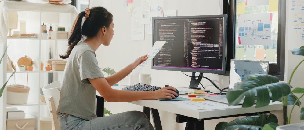woman using computer and holding a paper