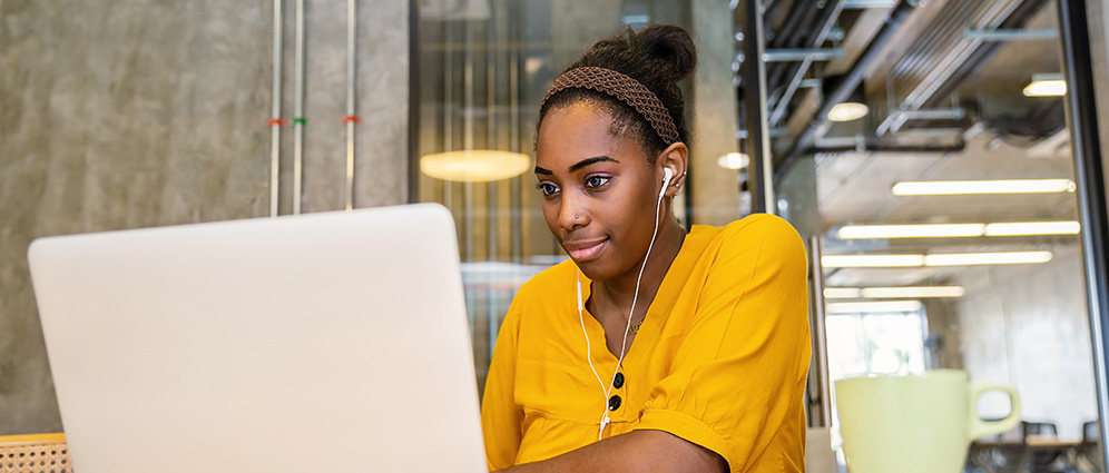 woman wearing wired earphones while looking at computer