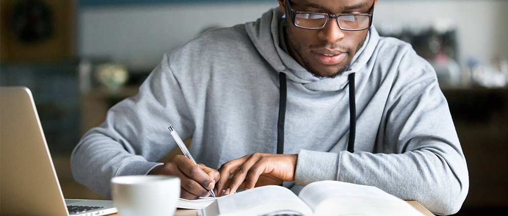 Young man studying with books and a laptop