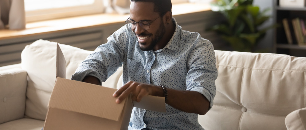 A man smiling while opening a package