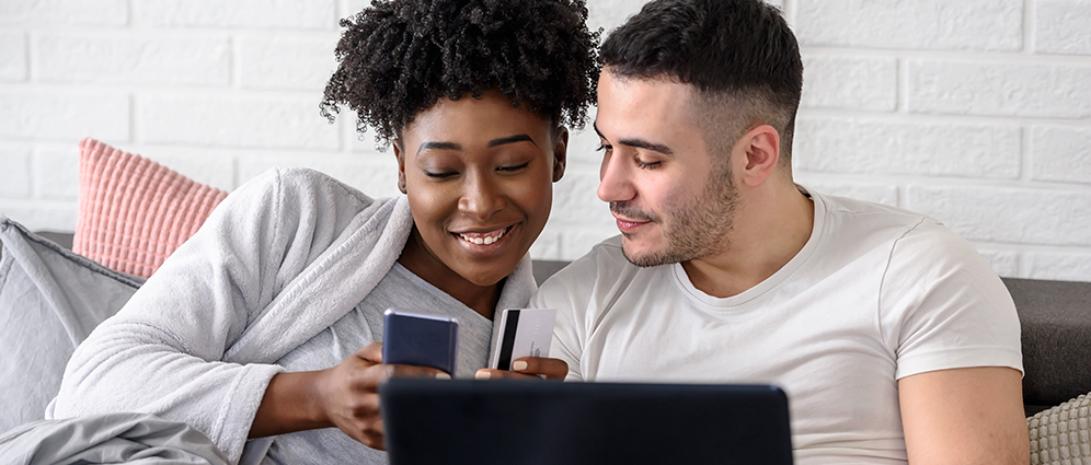 A couple smiling while paying a bill on their phone