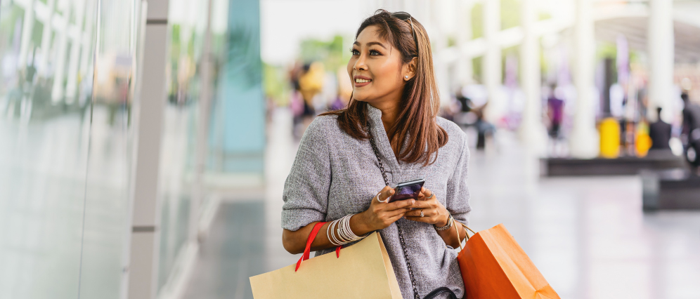 A woman smiling while carrying a shopping bag