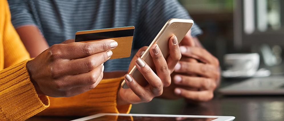 Close up of hands paying for a transaction with credit card on a mobile device.