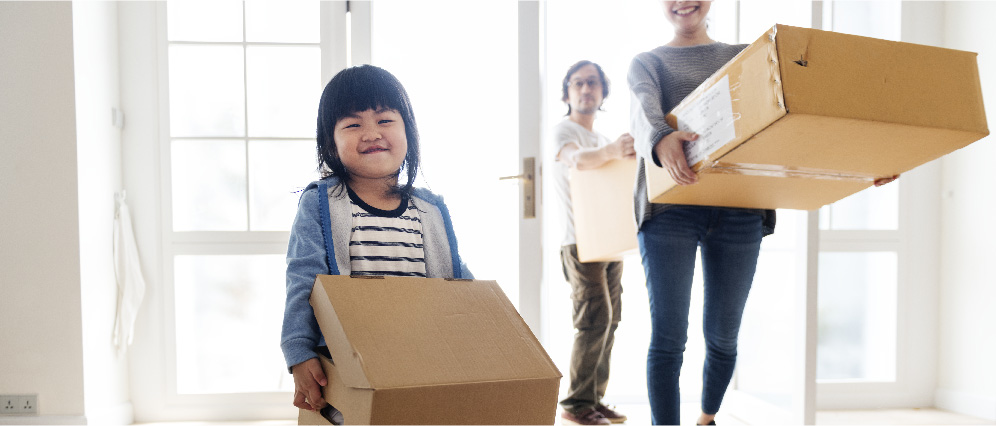 A young girl carrying a moving box and smiling