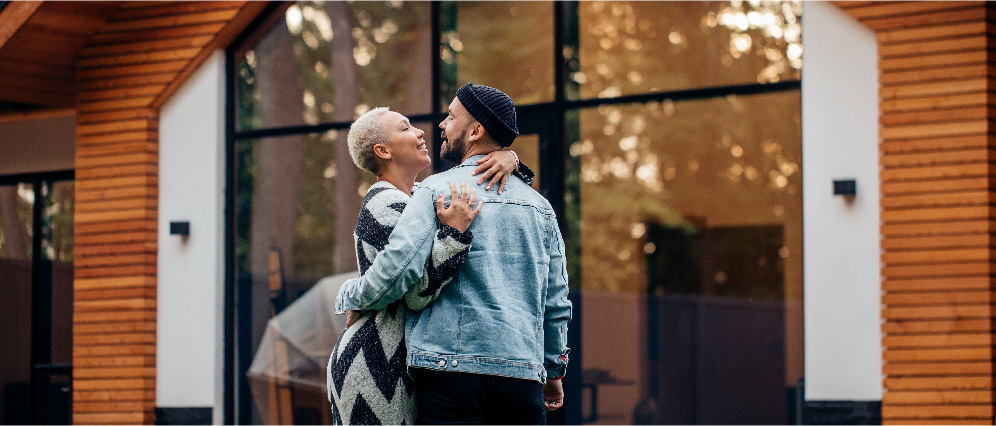First time homeowners hugging in front of their new home