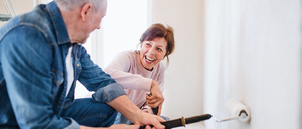 Happy couple painting a wall in their house